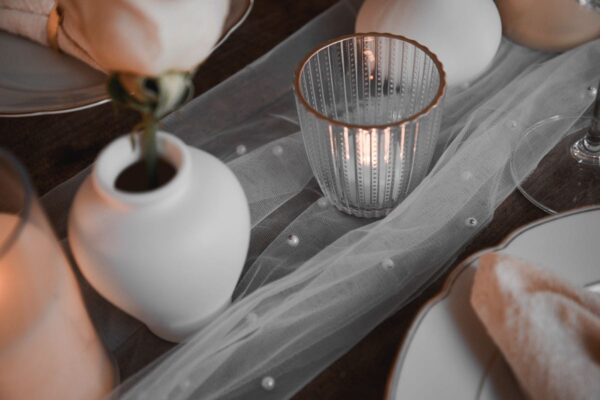 Ein Teelichtglas mit einem LED Teelicht und einer weißen Tonvase.